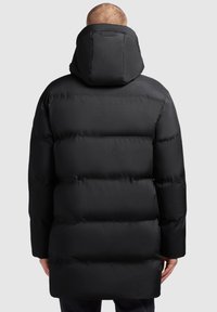 Svart pufferjacka med huva, kviltat mönster och lång silhuett, med en mjuk finish och diskreta detaljer.