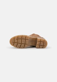 Helle Wanderschuhe mit Gummisohle, ausgestattet mit einem strukturierten Profil, gepolstertem Kragen und Mesh-Einsätzen für Atmungsaktivität.