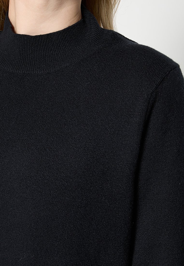 Schwarzer, gestrickter Pullover mit hohem Kragen. Verfügt über eine glatte Textur und gerippte Details am Hals. Enganliegend und ohne sichtbare Hardware.