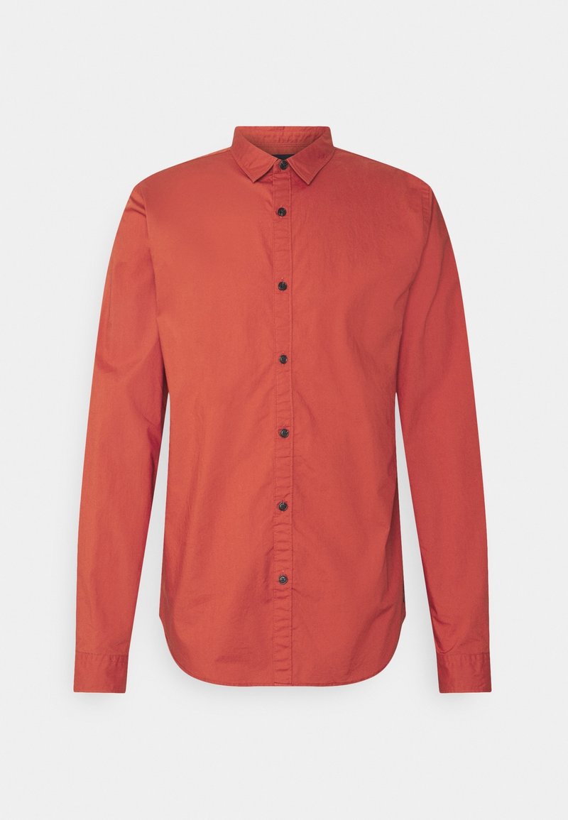 Camisa de manga larga con botones en color rojo, fabricada en algodón. Presenta un cuello puntiagudo, botones negros y un dobladillo curvado. Textura lisa en toda la prenda.