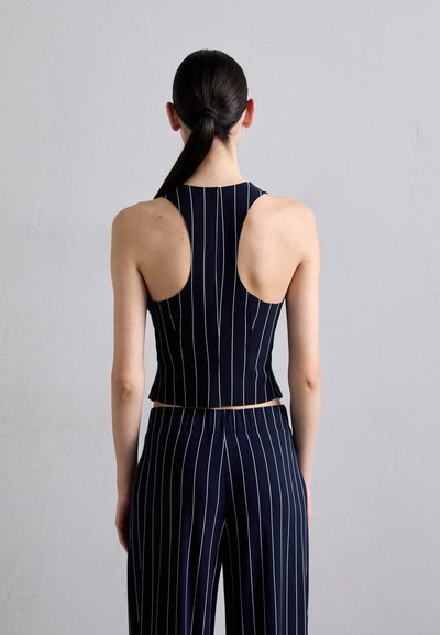 Navy, sleeveless cropped top with vertical white stripes. The back features wide armholes and a fitted design, paired with matching wide-leg pants.