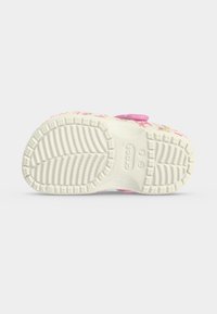 Λευκή λαστιχένια σόλα ροζ παιδικού κλογ με βαθύ ανάγλυφο και το λογότυπο Crocs στο κέντρο της σόλας.