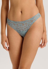Spitzen-Tanga in Türkis mit floralem Muster, ausgestattet mit einem dünnen Bund und Seiten, gefertigt aus leichtem, halbtransparentem Material.