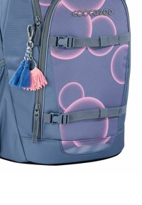 Blauer Rucksack mit Stoff im Blasenmuster, ausgestattet mit einer rosa und blauen Quaste, verstellbarem Tragegurt und Reißverschlüssen. Verstärkter Boden für Haltbarkeit.