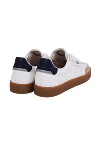 White leather sneakers with a gum rubber sole, rounded shape, navy blue heel accent, and perforated detailing on the sides.