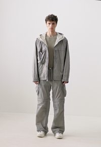 Light gray cargo jacket with hood and multiple pockets, paired with matching cargo pants. Smooth fabric with a relaxed fit. Plain design.