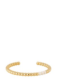 Bracelet jonc en ton or avec des perles rondes ornées d'accents blancs alternés, design ouvert, texture lisse et style minimaliste.