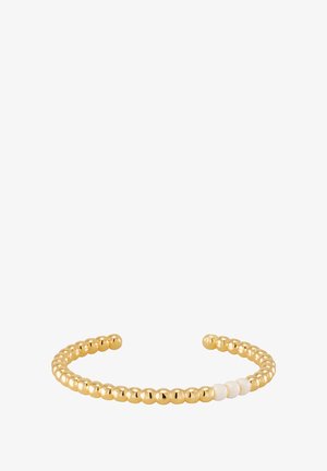 Bracelet jonc en ton or avec des perles rondes ornées d'accents blancs alternés, design ouvert, texture lisse et style minimaliste.