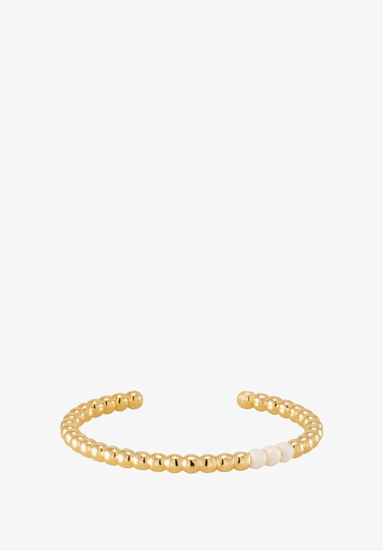 Bracelet jonc en ton or avec des perles rondes ornées d'accents blancs alternés, design ouvert, texture lisse et style minimaliste.