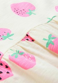 Lagana tkanina s kremastom podlogom sadrži uzorak ružičastih jagoda i zelenog lišća. Ruffled šav dodaje teksturu i detalje.