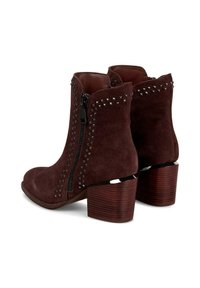 Botines de ante burdeos con acentos de tachuelas plateadas, cremalleras laterales dobles y tacones de madera cuadrados, con una textura suave.