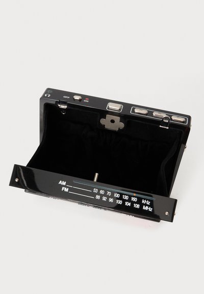 Pochette noire pliante avec tuner radio AM/FM intégré et boutons de contrôle sur le dessus, présentée ouverte sur fond blanc.