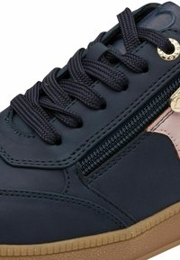 Navy blue sneaker with textured leather, flat laces, side zipper, and gum rubber sole. Features reinforced stitching and a subtle logo accent.