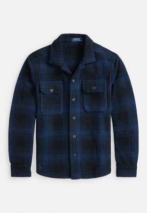 Tamsiai mėlynas ir juodas languotas flisinis marškinys su apykakle ir dviem krūtinės kišenėmis su sagomis, gulintis ant balto fono.