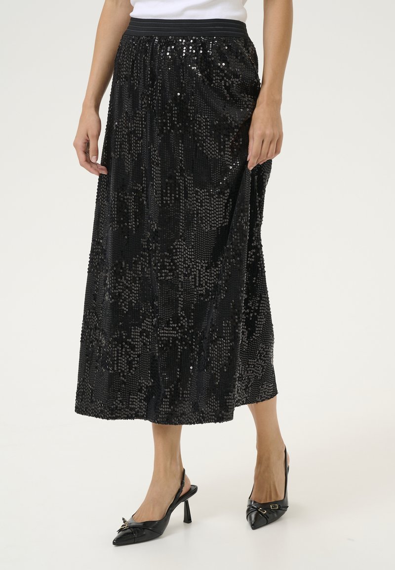 Černá maxi sukně s flitry s elegatním siluetou, která má přiléhavý pas a strukturovaný povrch. V kombinaci s černými lodičkami na slingback.
