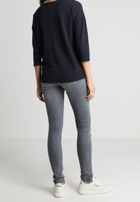 Marinblå kortärmad topp kombinerad med ljusgrå skinny jeans och vita sneakers, med en avslappnad passform och enkel design.