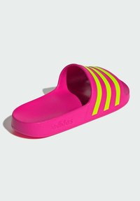 Pink slide sandal with three neon yellow stripes. Made of smooth plastic, featuring a contoured footbed and textured outsole. Adidas logo visible.