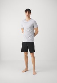 T-shirt gris à manches courtes en tissu doux, associé à un short noir. Les deux vêtements présentent un design simple et minimaliste avec une coupe décontractée.
