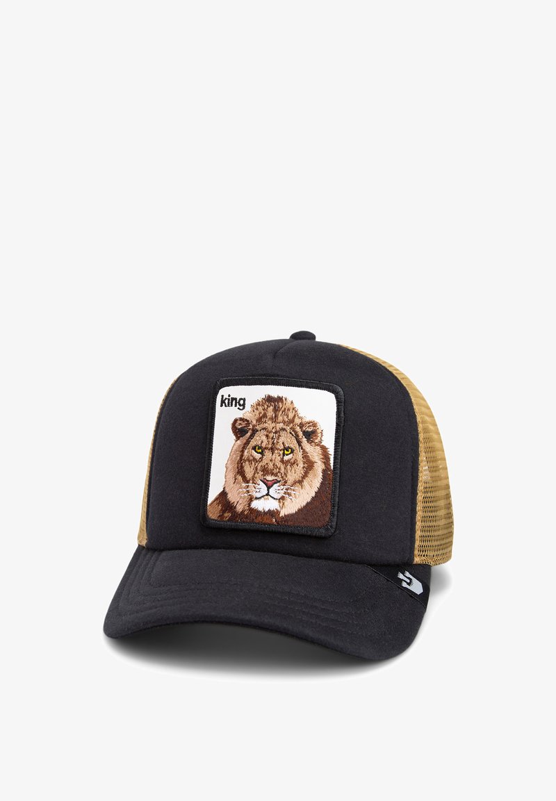 Black and tan trucker cap featuring a square patch with an embroidered lion, outlined in black. The visor is flat with textured fabric.