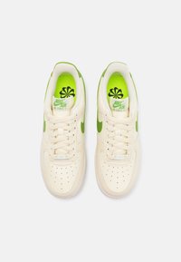 Nike Air Force 1-sneakers i krämfärgad läder med gröna accenter. Har texturerad tå, perforeringar för ventilering och vadderad krage.