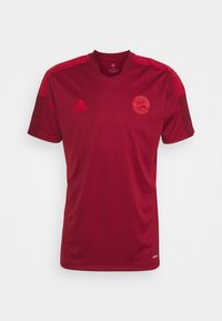 Camiseta deportiva roja de manga corta hecha de tela transpirable, con escote en V, rayas horizontales en los hombros y un logo del equipo en el pecho.