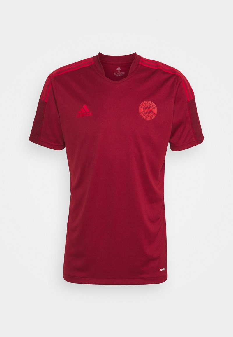 Camiseta deportiva roja de manga corta hecha de tela transpirable, con escote en V, rayas horizontales en los hombros y un logo del equipo en el pecho.
