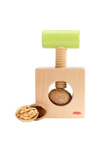 Wooden nutcracker with a green handle pressing a whole walnut inside, next to cracked walnut shell and walnut halves.