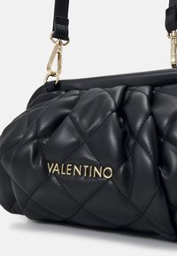 Quiltad svart läderhandväska med guld "Valentino"-logotyp, med axelrem och metallaccenter. Mjuk textur och rundad form.