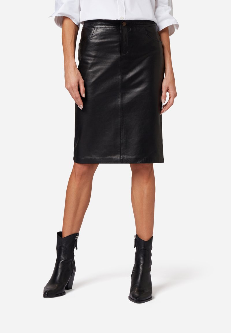 Svart läder midi-kjol med en åtsittande design, framsida med knappstängning och två sidofickor. Tillsammans med svarta klackade ankelboots.