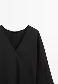 Černá halenka s výstřihem do V a širokými rukávy, vyrobená z hladké látky. Má minimalistický design a jemný šev podél švů.