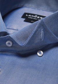 Niebieska koszula w kratę z kołnierzykiem, białymi guzikami i gładką teksturą materiału. Etykieta widoczna wewnątrz kołnierza.