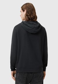 Felpa nera con cappuccio, dal taglio rilassato, caratterizzata da un cappuccio con cordino e polsini a coste. Il tessuto ha una texture liscia con una finitura opaca.