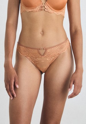 Kanten lingerie set in een warme beige kleur. De slip bevat delicate kantdetails, een V-vormige uitsnijding en kleine gouden hardware accenten.