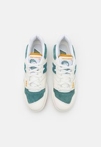 Bílé a tyrkysové tenisky New Balance 550 z kůže a semiše, s oranžovým brandingem, šněrovacím designem a gumovou podrážkou.