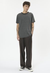 Gray striped t-shirt with a black crew neck, paired with brown wide-leg pants and black sneakers with white soles. Smooth fabric texture.