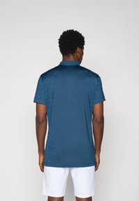 Navy blue polo shirt with a textured pattern on shoulders, short sleeves, and a classic collar. Material appears smooth and lightweight.