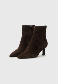 Bottines en daim marron avec un bout pointu, un talon slim et une fermeture éclair sur le côté. Texture lisse avec une silhouette chic.