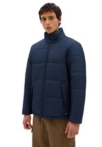 Navy blue padded jacket with a high collar, vertical stitching, front zip closure, and side pockets. Made from a smooth, lightweight material.