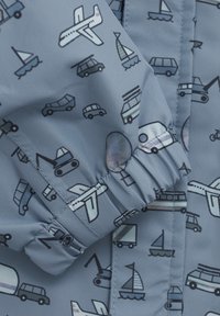 Blått tyg med ett mönster av fordon, inklusive bilar, flygplan och båtar. Har elastiska muddar och en slät, lätt glänsande textur.