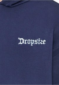 Granatowy hoodie z haftowanym białym logo "Dropsize" w stylu gotyckim. Tkanina ma gładką teksturę i prosty design.