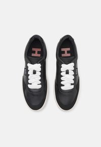 Black leather sneakers with white laces, rounded shape, and pink-accented insoles featuring an 'H'. Textured surface with perforations.