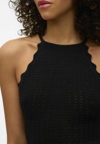 Top senza maniche in maglia nera con un motivo testurizzato, bordi scallop e spalline sottili, che mette in risalto una silhouette aderente.