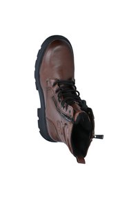 Botte en cuir marron avec semelle en caoutchouc noir, fermeture à lacets à l'avant, zip sur le côté et languette. Présente des détails en surpiqûre et un logo sur le côté.