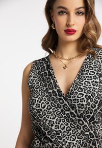 Rochie tip wrap cu imprimeu leopard, cu decolteu în V, realizată dintr-un material moale cu un aspect texturat și un design stratificat. Coliere din lanțuri aurii incluse.