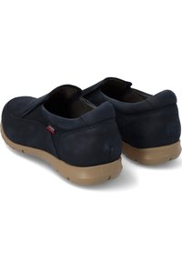 Zapatos de cuero azul marino con forma redondeada, textura suave y suela de goma flexible color marrón claro. Presentan una pequeña etiqueta con el logo en el lateral.