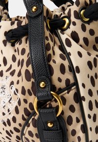 Saco de tecido suave, castanho e preto com manchas, equipado com uma alça texturizada preta, detalhes em dourado e fecho por cordão. Apresenta detalhes bordados.