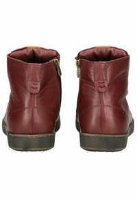 Botas de tobillo de cuero rojo con forma cónica, que cuentan con una cremallera lateral y suela texturizada. Acabado suave con mínimos acentos de costura.