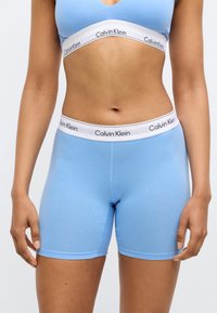 Ανοιχτό μπλε σορτς από βαμβακερό μείγμα με εφαρμοστή σχεδίαση. Διαθέτει λευκή ταινία με το λογότυπο "Calvin Klein" σε μαύρο, με λεία υφή και αρμονικά τελειώματα.