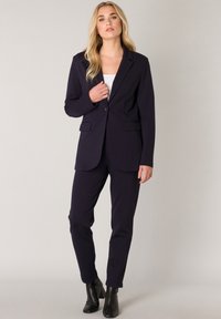 Marineblazer en bijpassende broek, gemaakt van soepel stof. De blazer heeft een enkele knoopsluiting en notch-lapels; slank fit ontwerp.
