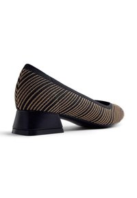 Chaussure pour femme à talon bas, en tissu tricoté noir et beige rayé, avec un talon et des bordures noirs unis, vue en angle latéral.